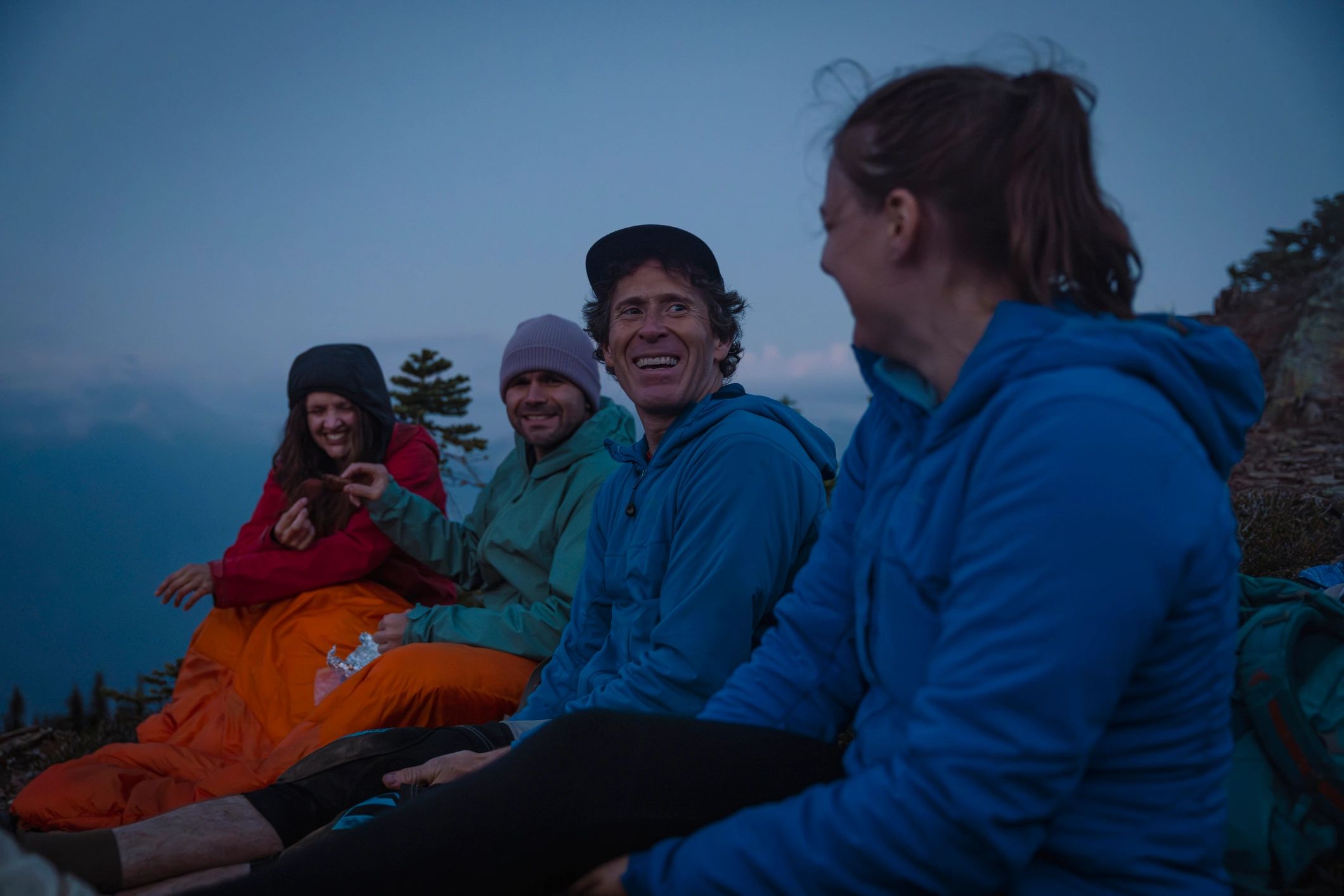 Backpackers relaxing on a mountain summit at twilight