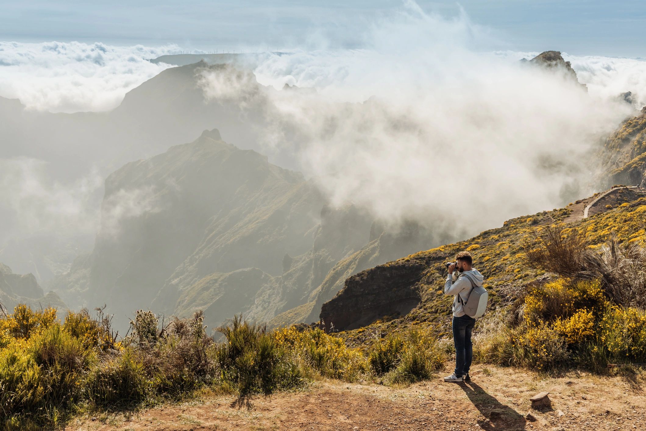 Outdoor photographer standing on a mountain ridge above misty valleys